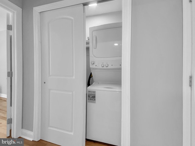 washroom with hardwood / wood-style flooring and stacked washer and dryer