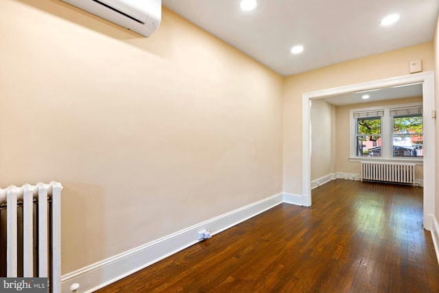 empty room with wood-type flooring, a wall mounted AC, and radiator heating unit