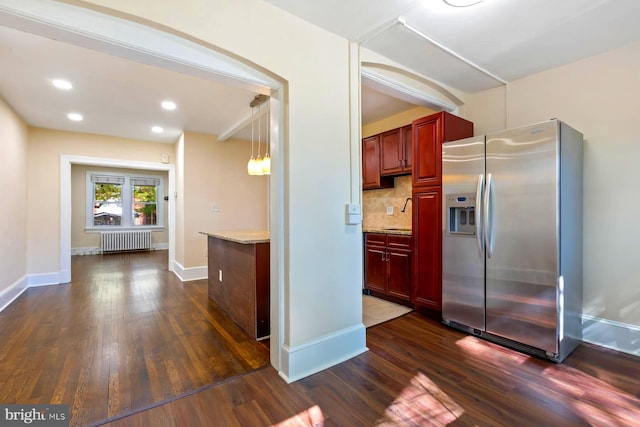 kitchen featuring decorative backsplash, radiator, dark wood-type flooring, and stainless steel refrigerator with ice dispenser