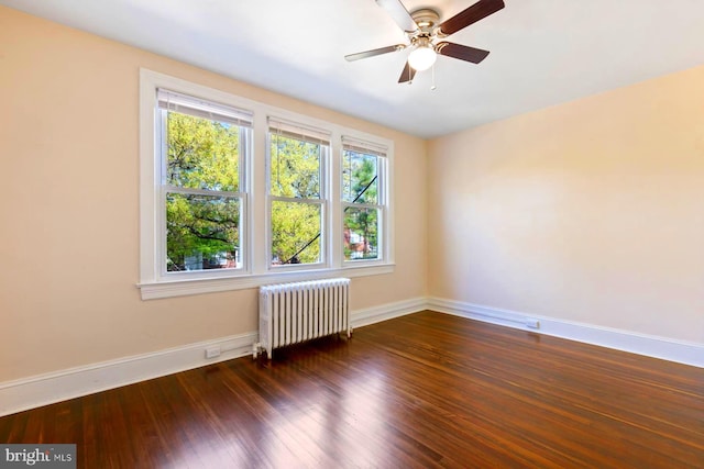 empty room featuring ceiling fan, radiator heating unit, and dark wood-type flooring