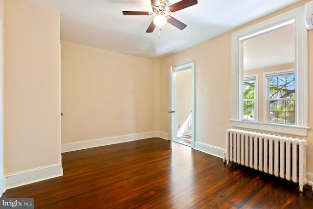 empty room featuring radiator heating unit, ceiling fan, and dark hardwood / wood-style floors