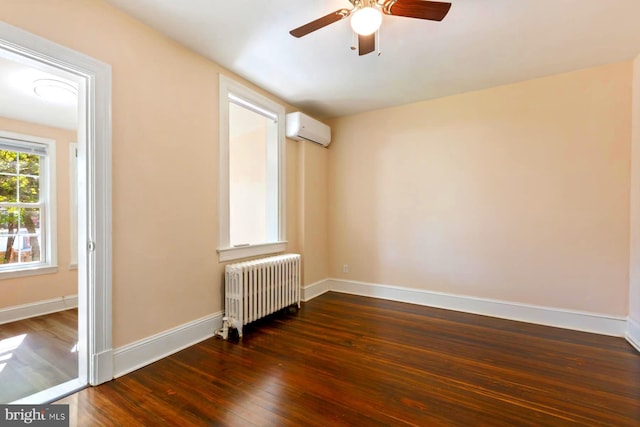 spare room with ceiling fan, hardwood / wood-style flooring, an AC wall unit, and radiator heating unit