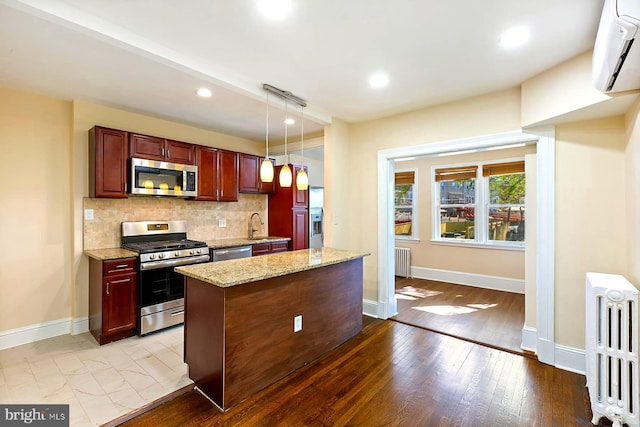 kitchen featuring decorative backsplash, light hardwood / wood-style flooring, radiator heating unit, light stone counters, and stainless steel appliances