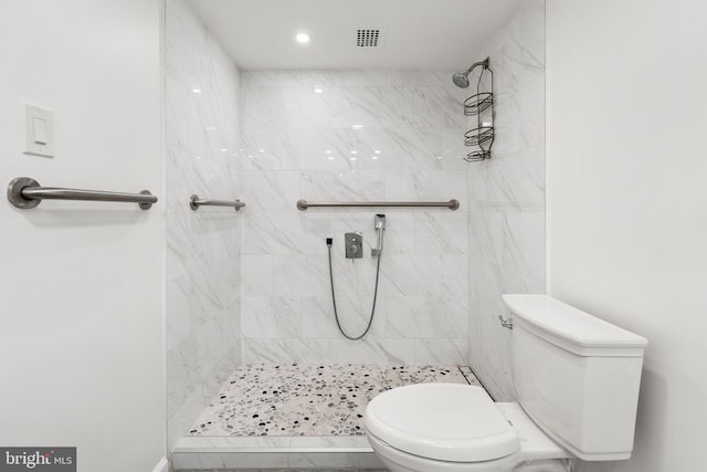 bathroom with a tile shower and toilet