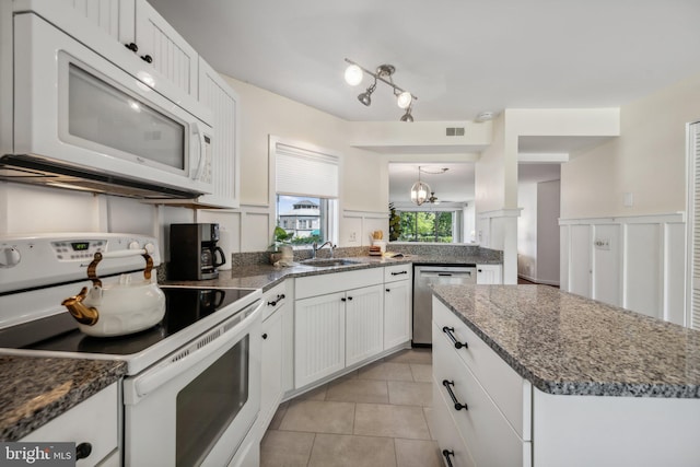 kitchen with white cabinets, light tile patterned floors, an inviting chandelier, sink, and white appliances