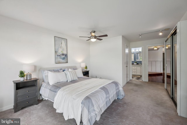 bedroom featuring rail lighting, ensuite bath, carpet floors, and ceiling fan