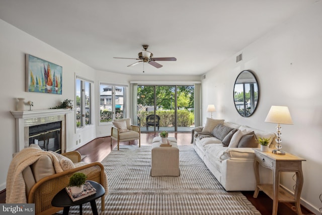 living room featuring a premium fireplace, hardwood / wood-style floors, plenty of natural light, and ceiling fan