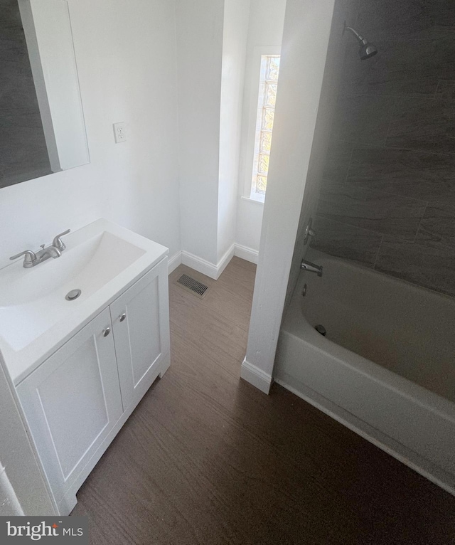 full bath featuring shower / tub combination, wood finished floors, vanity, visible vents, and baseboards