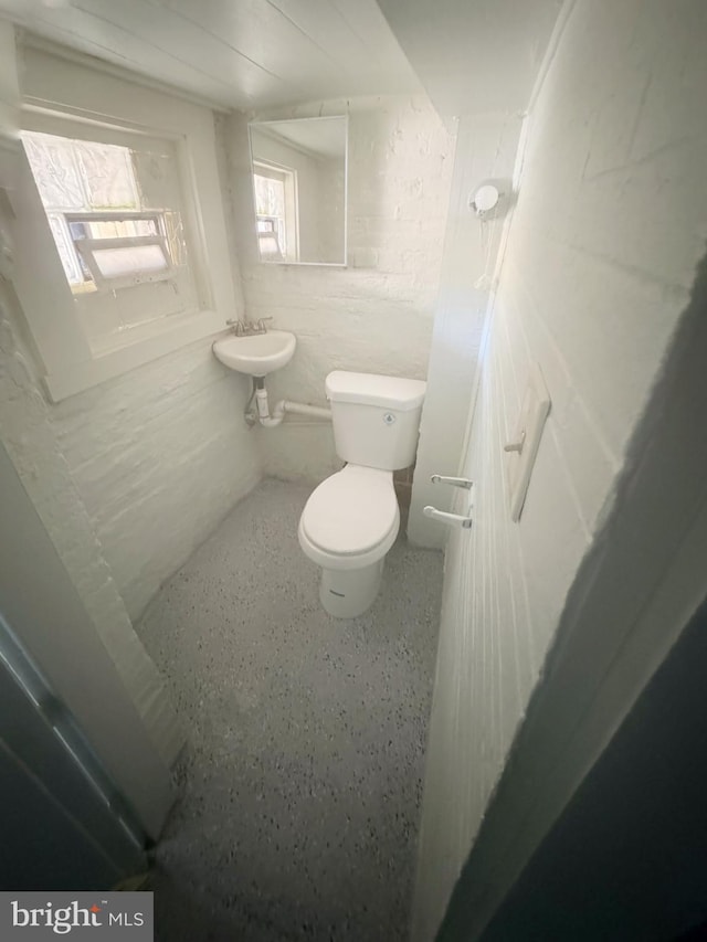 half bath with toilet, a sink, and speckled floor