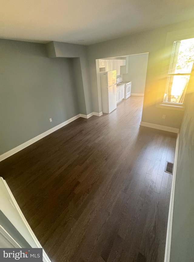 unfurnished room with dark wood-type flooring, visible vents, and baseboards