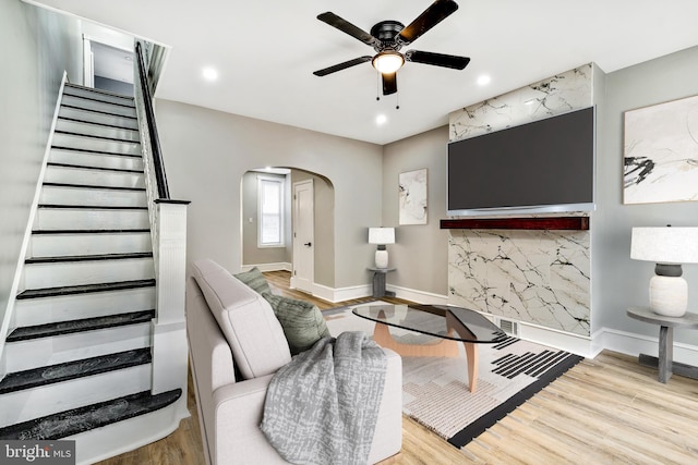 living area featuring arched walkways, stairway, wood finished floors, and baseboards