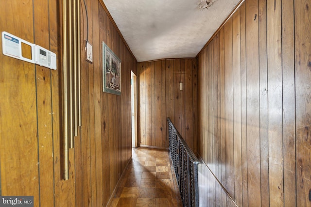 corridor featuring wood walls and a textured ceiling