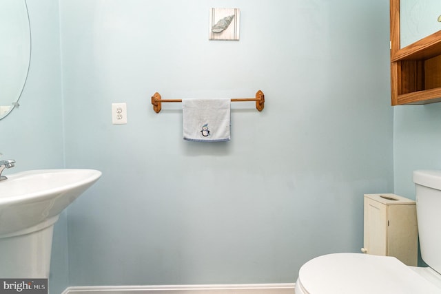 half bathroom featuring a sink, toilet, and baseboards