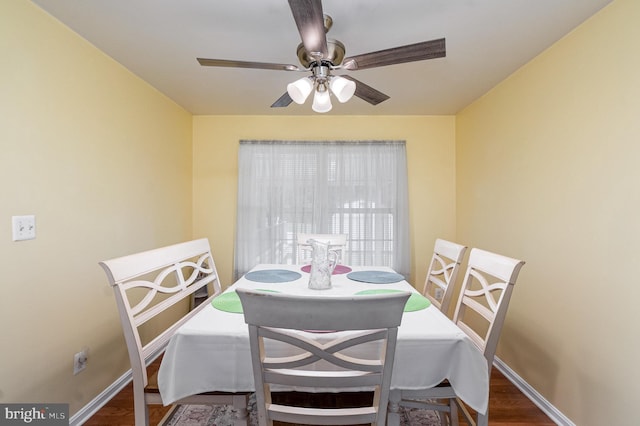 dining space with a ceiling fan, dark wood finished floors, and baseboards