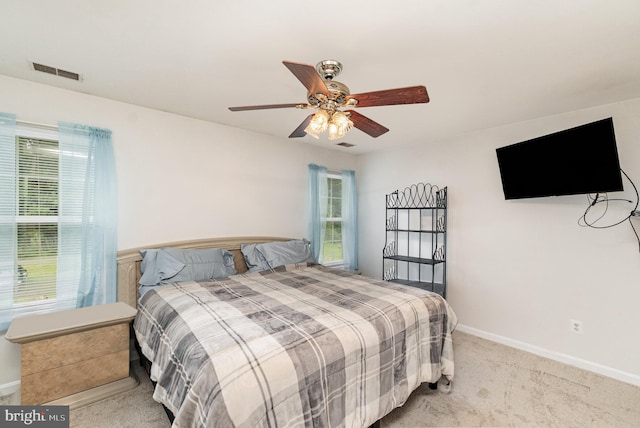 bedroom featuring a ceiling fan, visible vents, light carpet, and baseboards