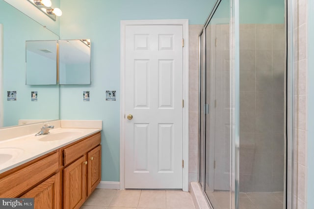 bathroom with double vanity, a sink, a shower stall, and tile patterned floors