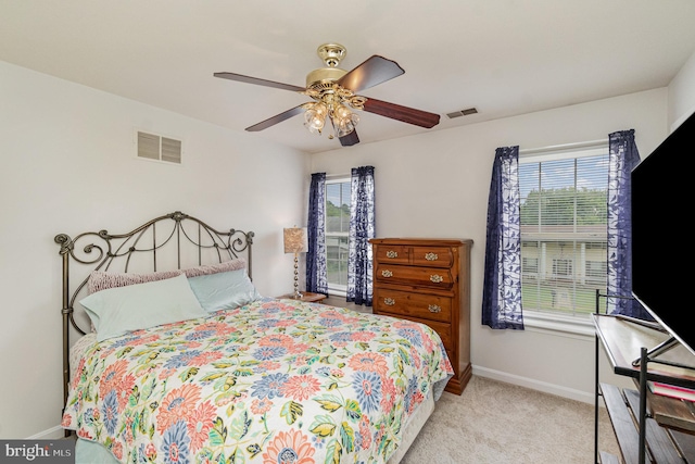 bedroom featuring a ceiling fan, visible vents, light carpet, and baseboards