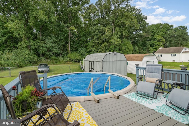 outdoor pool featuring an outbuilding, a deck, fence, a lawn, and a storage unit