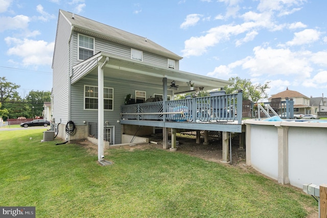 back of house with a deck, a lawn, cooling unit, and an outdoor pool