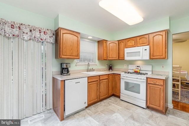 kitchen featuring white appliances, visible vents, brown cabinetry, light countertops, and a sink