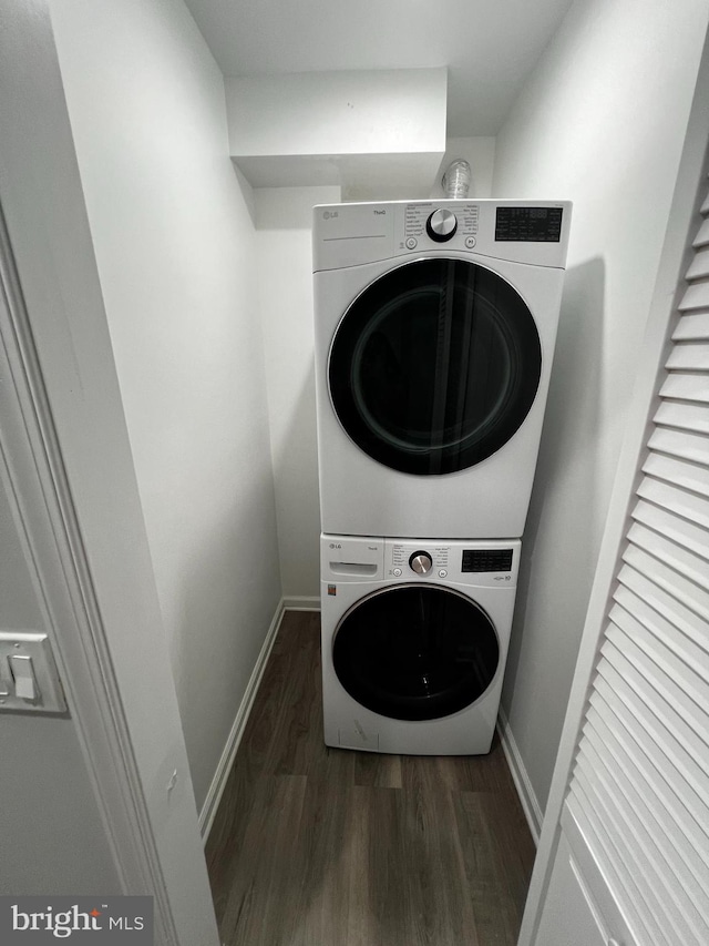 laundry room featuring dark hardwood / wood-style flooring and stacked washer / drying machine