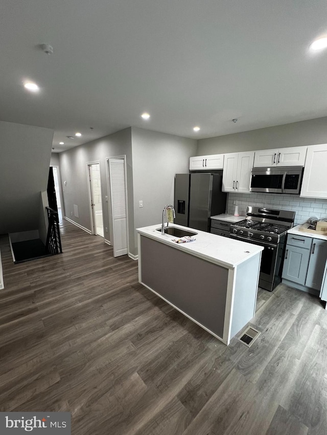 kitchen with sink, appliances with stainless steel finishes, dark wood-type flooring, decorative backsplash, and white cabinetry