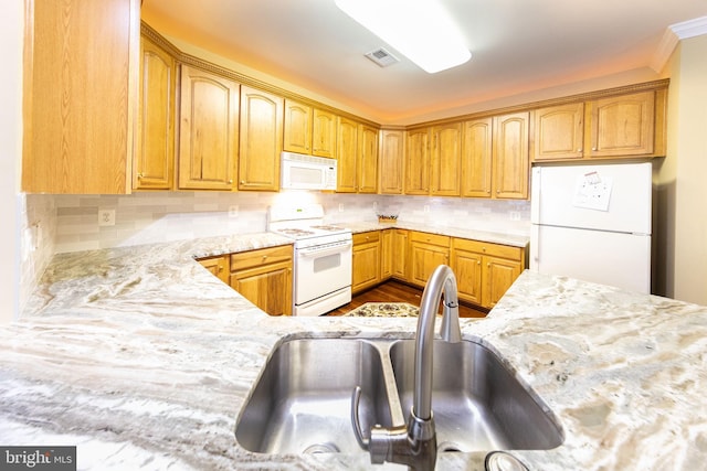 kitchen featuring hardwood / wood-style flooring, white appliances, light stone counters, sink, and tasteful backsplash