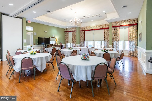 dining room with an inviting chandelier, wood-type flooring, and a tray ceiling