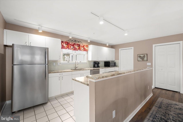 kitchen with sink, white cabinetry, appliances with stainless steel finishes, a center island, and light wood-type flooring