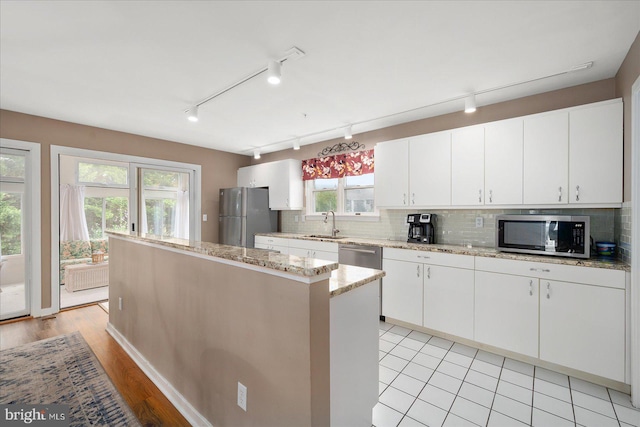 kitchen with light wood-type flooring, sink, white cabinetry, a kitchen island, and stainless steel appliances