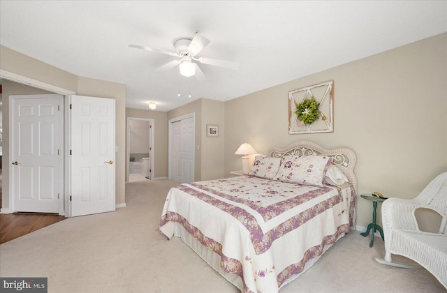 carpeted bedroom featuring a closet, ensuite bath, and ceiling fan