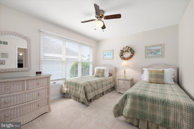 bedroom with light carpet, ceiling fan, and a textured ceiling