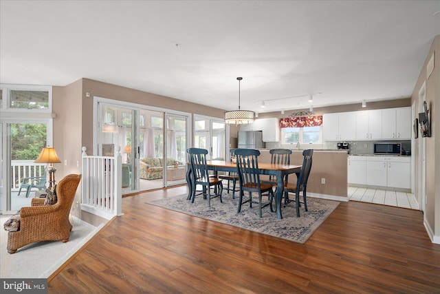 dining area featuring a notable chandelier, hardwood / wood-style flooring, and track lighting