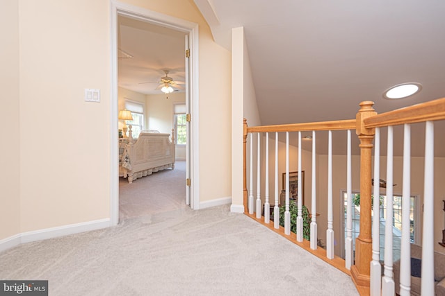 hallway with baseboards and light colored carpet