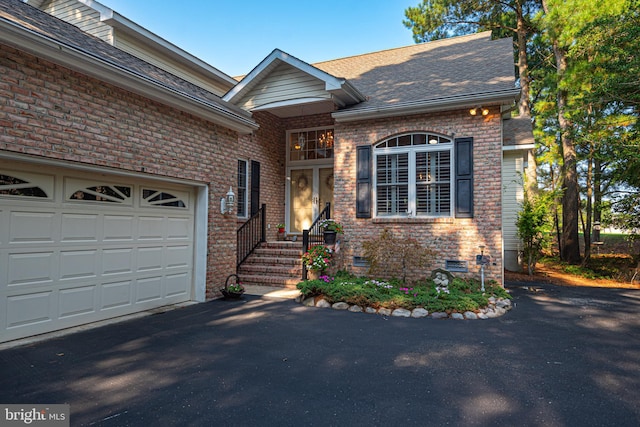 view of front of home featuring aphalt driveway, crawl space, brick siding, and an attached garage