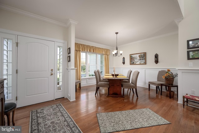 entrance foyer with a chandelier, a wainscoted wall, wood finished floors, and crown molding