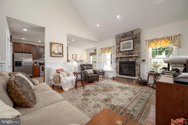 living room featuring a wealth of natural light, hardwood / wood-style flooring, and a stone fireplace