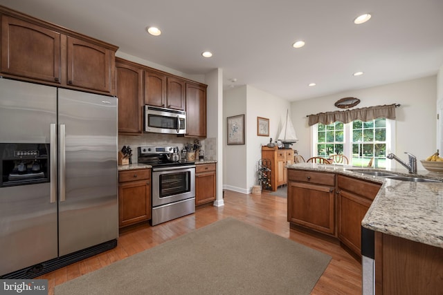 kitchen with light hardwood / wood-style floors, appliances with stainless steel finishes, sink, and tasteful backsplash