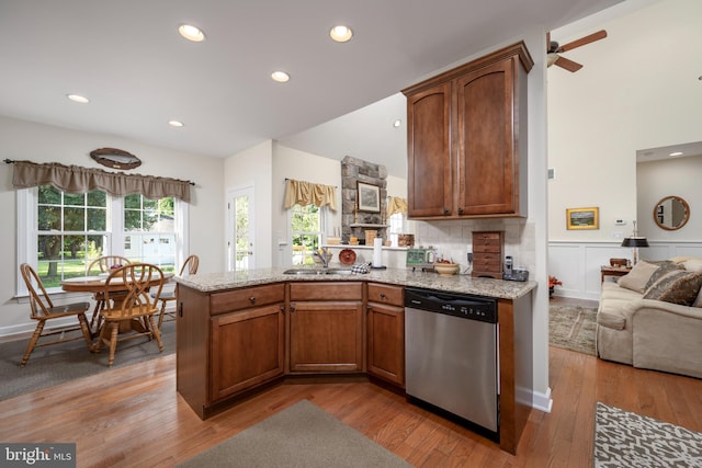 kitchen with sink, light wood-type flooring, decorative backsplash, light stone countertops, and stainless steel dishwasher