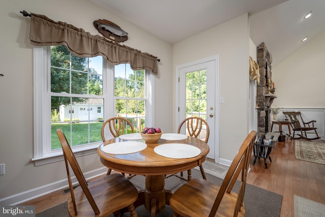 dining area with hardwood / wood-style floors, vaulted ceiling, and a healthy amount of sunlight