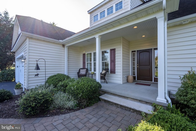 doorway to property with covered porch and roof with shingles