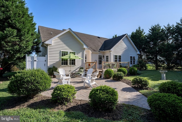 back of property featuring a yard, a patio, a shingled roof, and a wooden deck