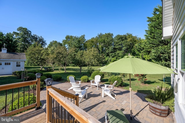 wooden deck featuring an outdoor fire pit, an outdoor structure, a patio area, and a yard