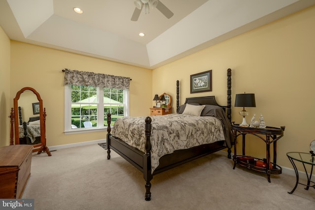 bedroom featuring ceiling fan, light carpet, and a tray ceiling