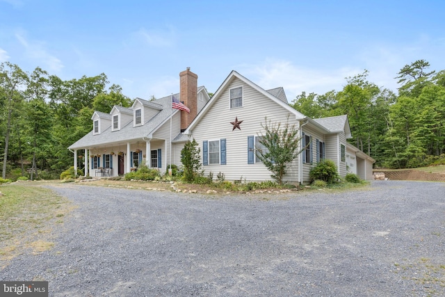 cape cod home featuring a porch and a garage