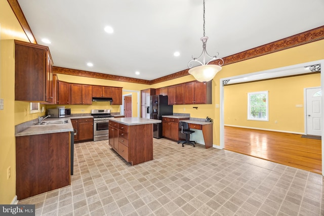 kitchen with a kitchen island, light hardwood / wood-style floors, sink, decorative light fixtures, and stainless steel appliances