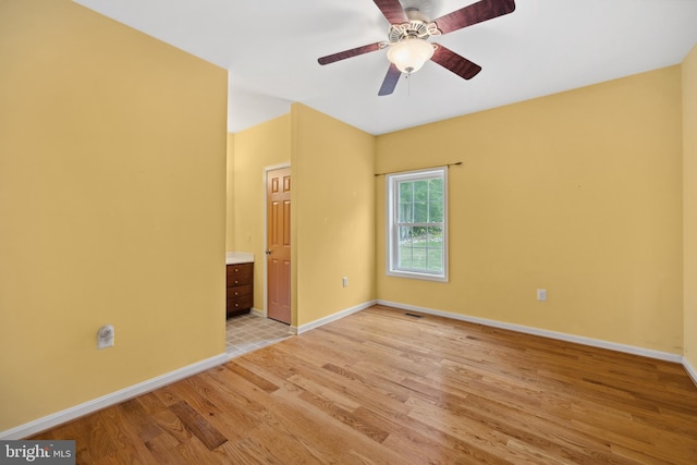 unfurnished bedroom featuring ceiling fan, ensuite bath, and light hardwood / wood-style floors