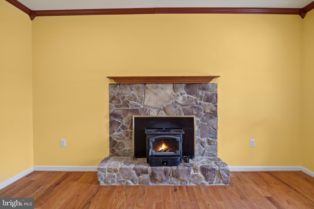 interior details featuring hardwood / wood-style flooring, a wood stove, crown molding, and a stone fireplace