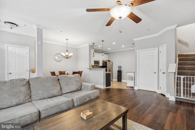 living room featuring dark wood-type flooring, ceiling fan with notable chandelier, and ornamental molding