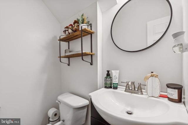 bathroom featuring toilet, vaulted ceiling, and sink